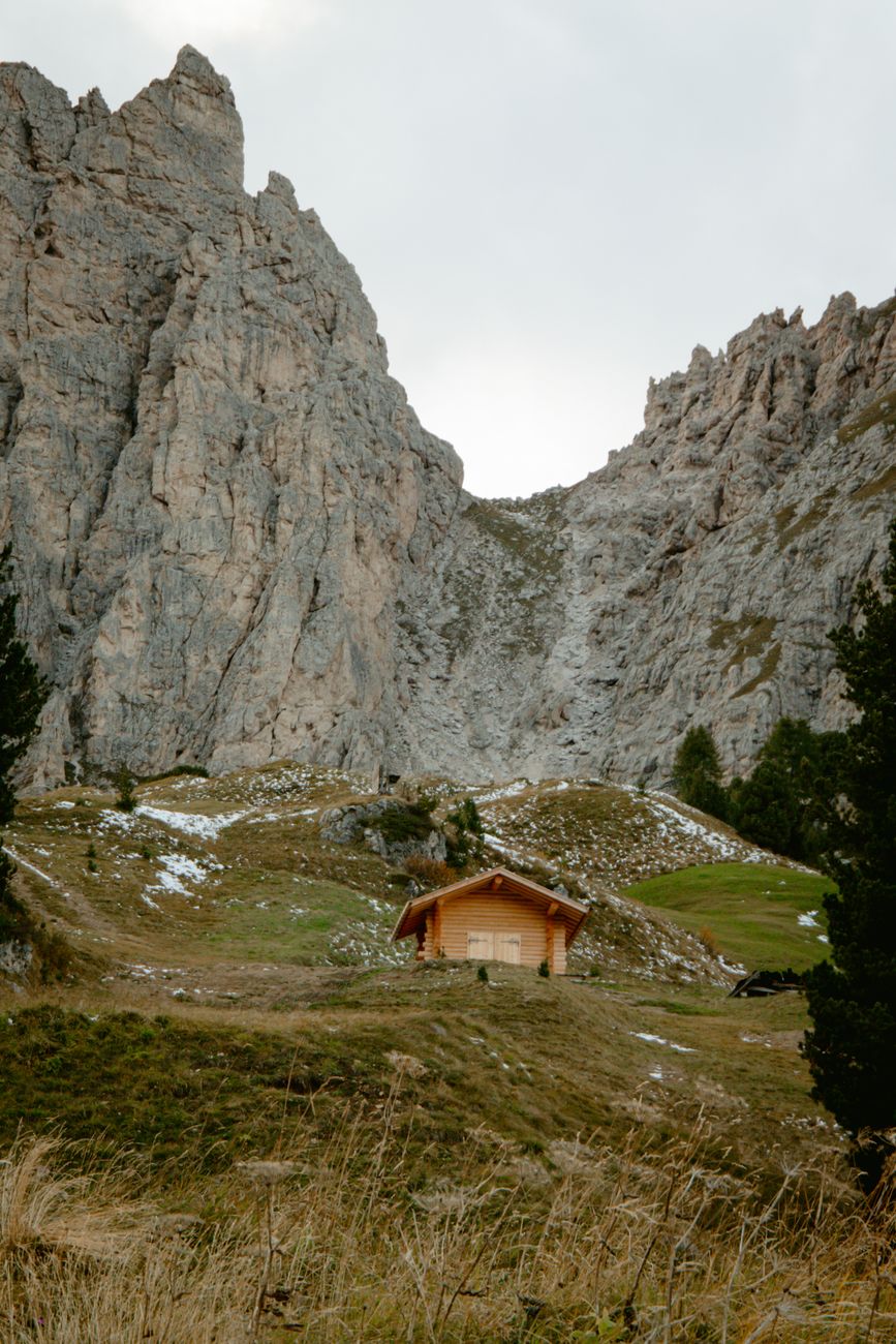 Sunlit alpine hut beneath towering Dolomite peaks